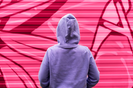 Young woman in hood in purple violet hoodie from back on pink red abstract modern background viva magenta color and very peri copy space mockup friendlyの写真素材