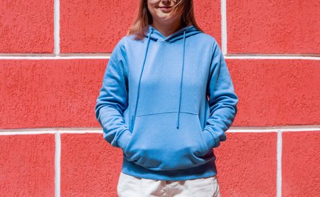 Smiling young woman in blue purple hoodie on red background copy space mockup friendlyの写真素材