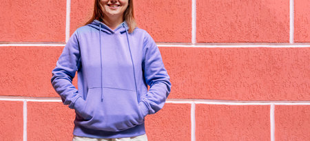 Smiling young woman in blue purple hoodie on red background copy space mockup friendlyの写真素材