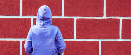 rear view of woman dressed in hooded blue purple sweatshirt against red wall background , mockup friendly, textile business clothing Copy space Bannerの写真素材