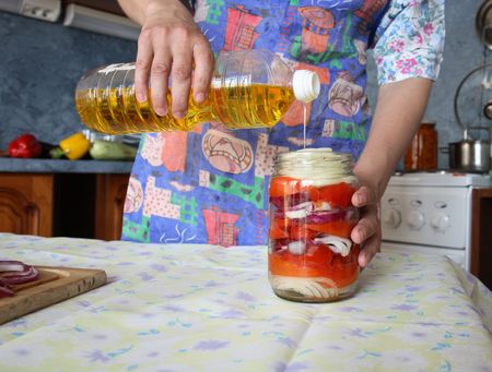 mistress pours sunflower-seed oil in vegetable saladの写真素材