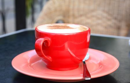 Fragrant coffee with a dairy skin in a red cupの写真素材