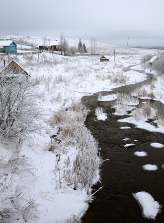 Winter rural landscape with wooden houses and the riverの写真素材