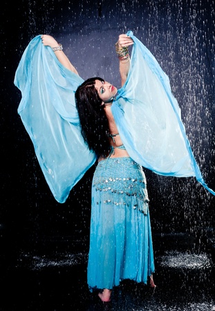 girl executes east dance in the rain against a dark backgroundの写真素材