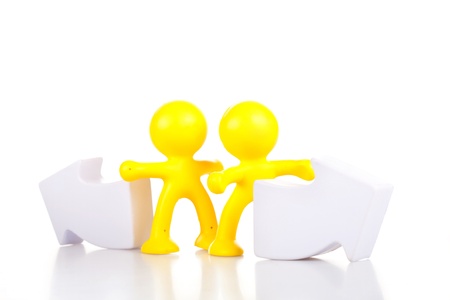 Two smiling toy little men stand near the arrows specifying a direction. The concept of a difficult choice.の写真素材