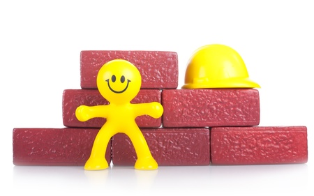 One smiling toy little man near to a heap of bricks. The building concept.の写真素材