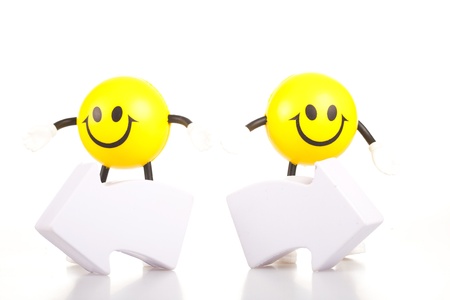 Two smiling toy little men stand near the arrows specifying a direction. The concept of a difficult choice.の写真素材