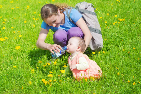 Mum gives to drink to the daughter water on walkの写真素材