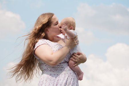 Mother with baby on the meadow under blue sky