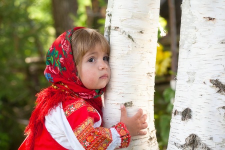 little girl in the Russian national dress embraces a birchの写真素材