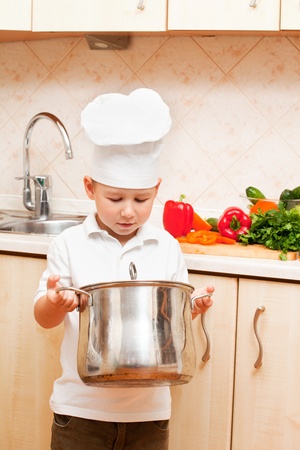 little boy on kitchen helps to make a dinnerの写真素材