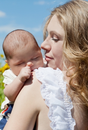 Young mother with the baby among blossoming sunflowersの写真素材