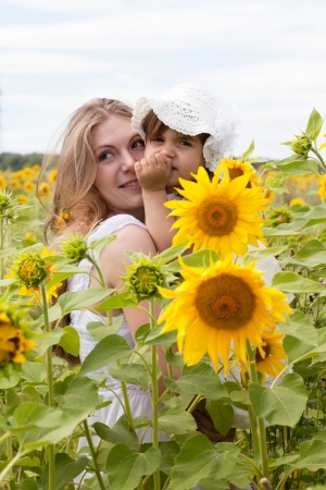 Happy mother with the daughter in the field with sunflowersの写真素材