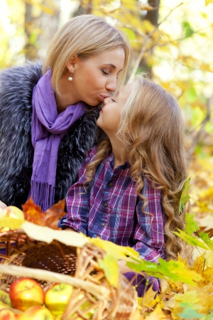 Happy mum and the daughter play autumn park on the fallen down foliage の写真素材