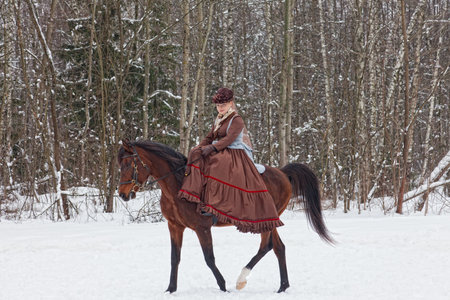 Eleganny woman in riding habit sits astride a bay Arab racer