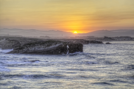 Beautiful sunset and stone arches on Playa de las Catedrales during inflow, Spainの写真素材