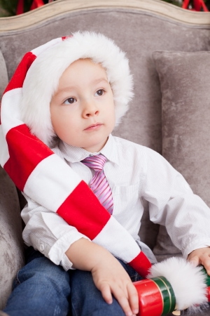  little boy sits in a chair in Santa Claus's capの写真素材