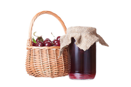 Bank with cherry jam and a basket with ripe cherriesの写真素材