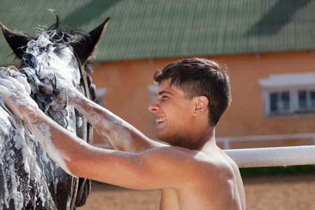 Young sexy man washes a horseの写真素材