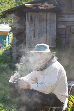 bee-keeper in a protective suit with bee smoker for smoking of beesの写真素材