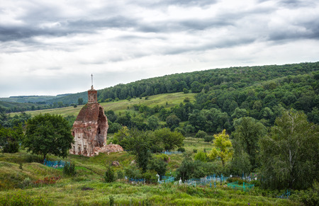 destroyed old church and cemetery on the hill in cloudy summer morningの写真素材