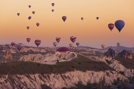 Multi-colored balloons fly over rocks in Cappadocia at sunriseの写真素材