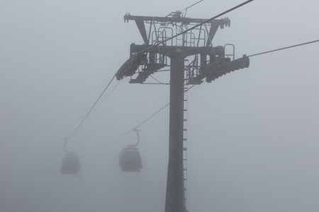 Cabs ropeway leading to heavy fogの写真素材