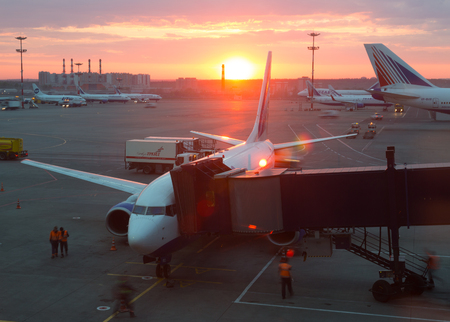 RUSSIA, DOMODEDOVO - MAY 11, 2015: Airplane in the middle of the ladder at the airport at sunset of the sun. Preparation of the aircraft for boarding passengers.のeditorial素材