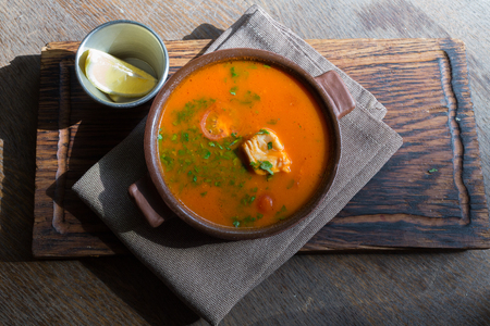 Marmitako soup in a ceramic bowl on a wooden boardの写真素材