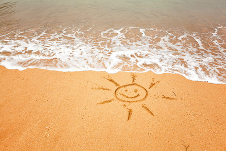 Smiling sun - drawing on the sand on a tropical beachの写真素材