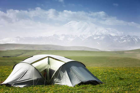 Tourist tent stands on the grass mountains backgroundの写真素材