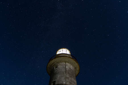Working lighthouse and starry skyの写真素材