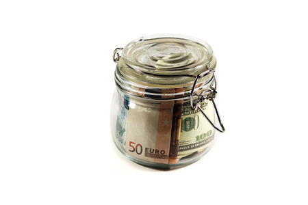 Glass jar filled with banknotes of different countriesの写真素材
