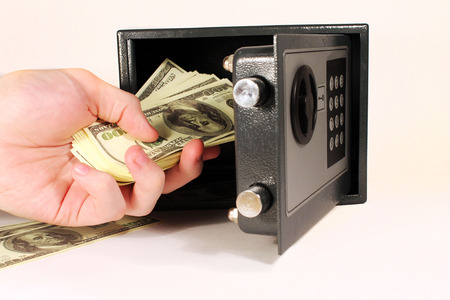 Hand putting hundred dollar notes  in a mini safeboxの写真素材