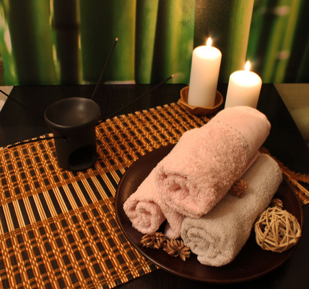 Spa still-life with candles, various incense sticks and a towel on bamboo backgroundの写真素材
