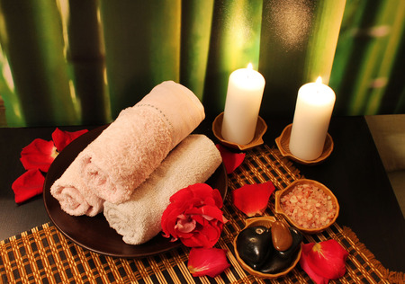 Spa still-life with candles, sea salt, towel, massage stones and rose petalsの写真素材
