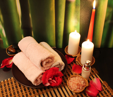 Spa still-life with candles, sea salt, towel, massage stones and rose petalsの写真素材