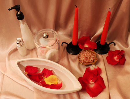 Spa still-life with candles, rose petals and objects for spa procedures on a background of pink silkの写真素材