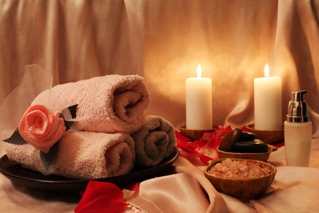 Spa still-life with candles, rose petals and objects for spa procedures on a background of pink silkの写真素材