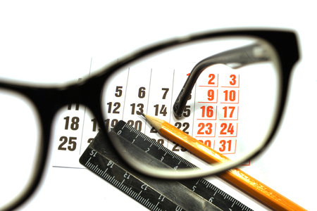 Still life of calendar sheet, pencil and ruler viewed through the glasses eyepieceの写真素材