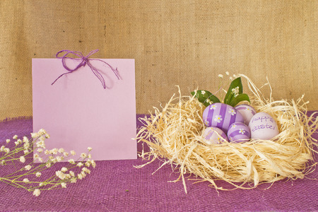 Egg with violet flowers and an inscription Happy Easter on a background  of congratulatory sheet and a sackingの写真素材