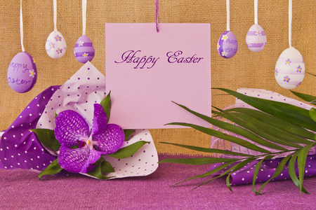 Eggs and congratulatory sheet hanging on a rope on the background of a sacking and violet orchidの写真素材