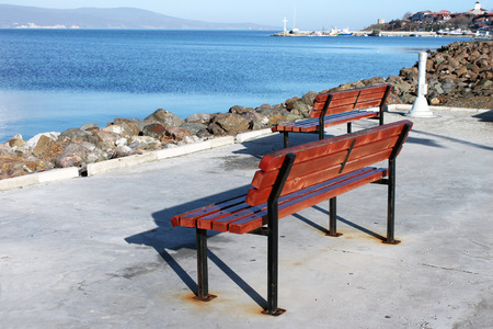 Wooden brown bench standing on the promenade of a sea gulfの写真素材