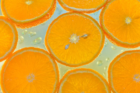Fresh orange slices sliced by circles lying in the water with bubbles