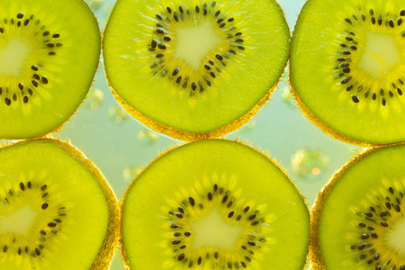 Fresh kiwi slices sliced by circles lying in the water with bubblesの写真素材