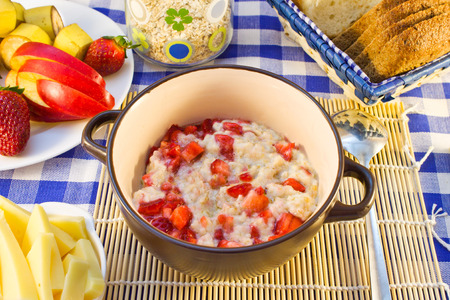 Oat porridge with strawberries, cheese, cereals in a glass jar, fruit in the a saucer.の写真素材