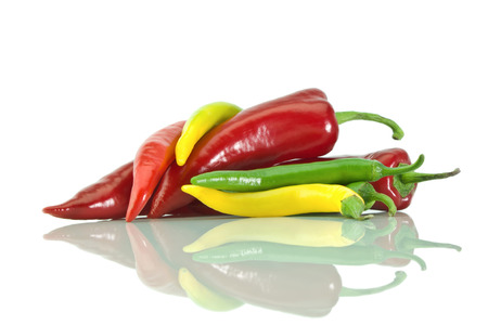 Peppers yellow, green and red colors and it's reflection on a white  isolated backgroundの写真素材