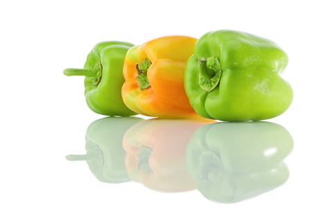 Green and yellow bell peppers and it's reflection on a white isolated backgroundの写真素材