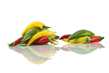 Peppers yellow, green and red colors and it's reflection on a white  isolated backgroundの写真素材