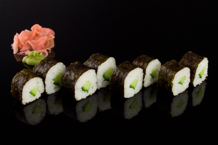 Sushi roll with cucumber on the black background with reflectionの写真素材